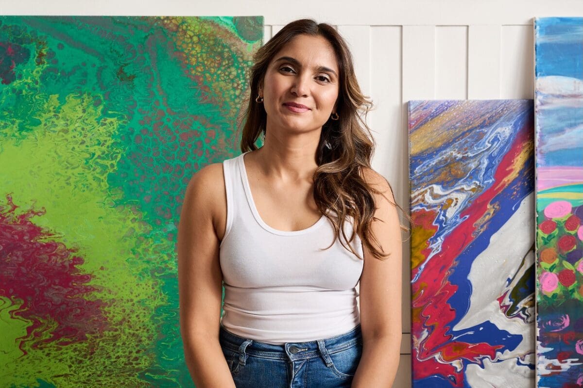 Artist sitting in front of her paintings