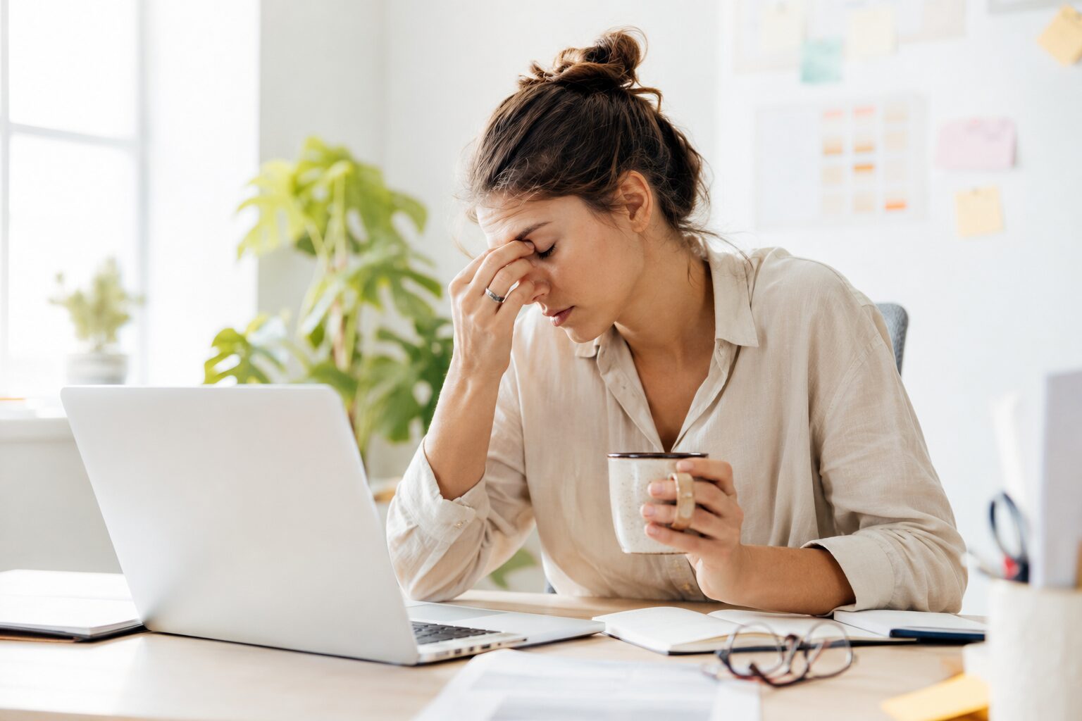 A person experiencing long COVID and chronic fatigue sits exhausted at a bright home office desk, holding a coffee mug while looking drained in front of a laptop. The image represents persistent fatigue, brain fog, and burnout, highlighting how Ayurveda aims to restore energy by addressing the root causes of imbalance rather than only managing symptoms.